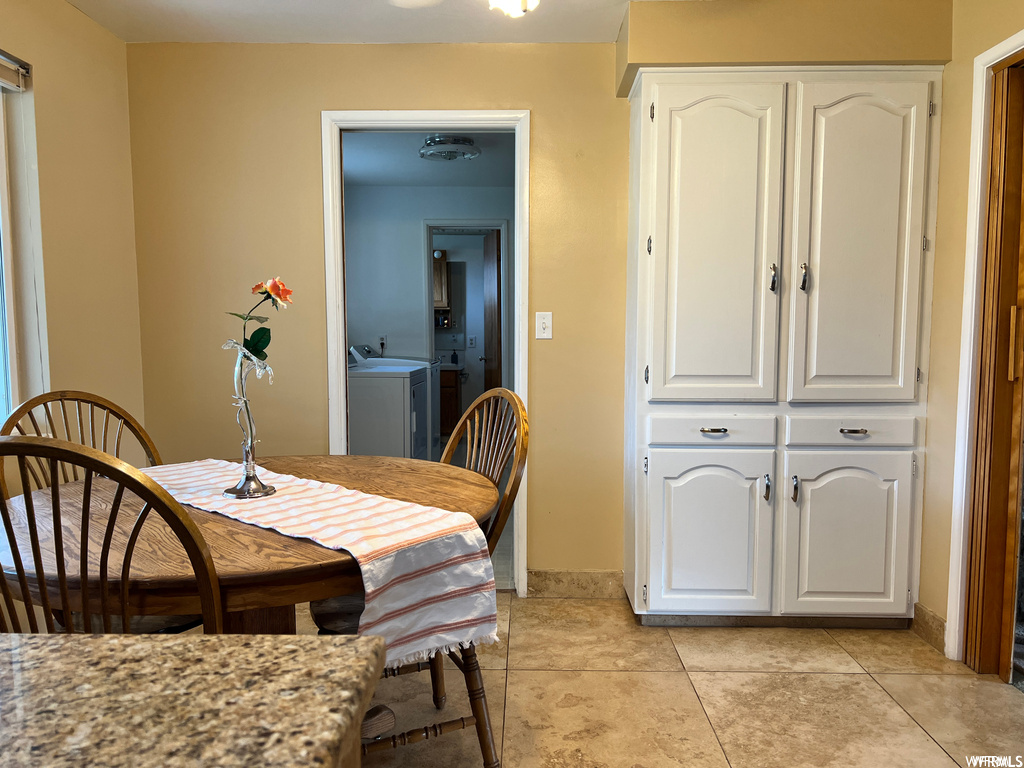 Tiled dining space with washing machine and clothes dryer