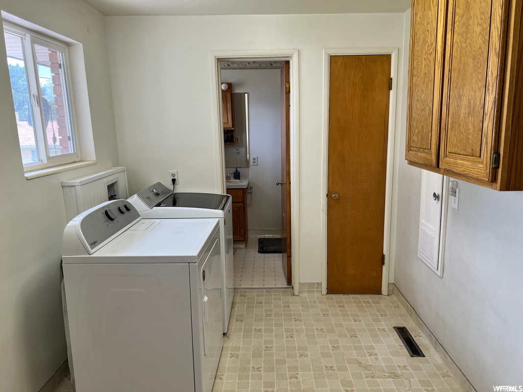 Laundry area with cabinets, hookup for a washing machine, light tile floors, and washing machine and dryer