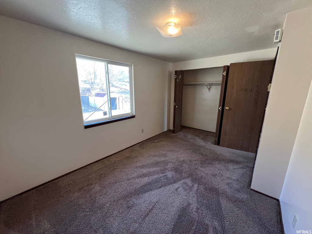 Unfurnished bedroom with carpet floors, a closet, and a textured ceiling