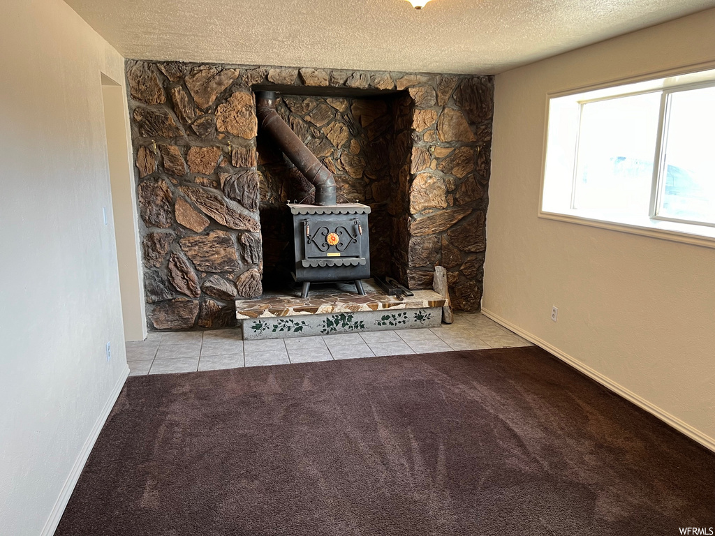 Room details with a wood stove, light carpet, and a textured ceiling
