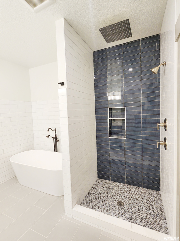 Bathroom featuring independent shower and bath, a textured ceiling, tile walls, and tile flooring