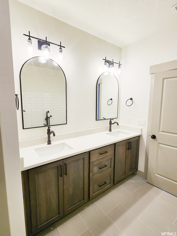 Bathroom featuring tile floors, double sink vanity, and a textured ceiling