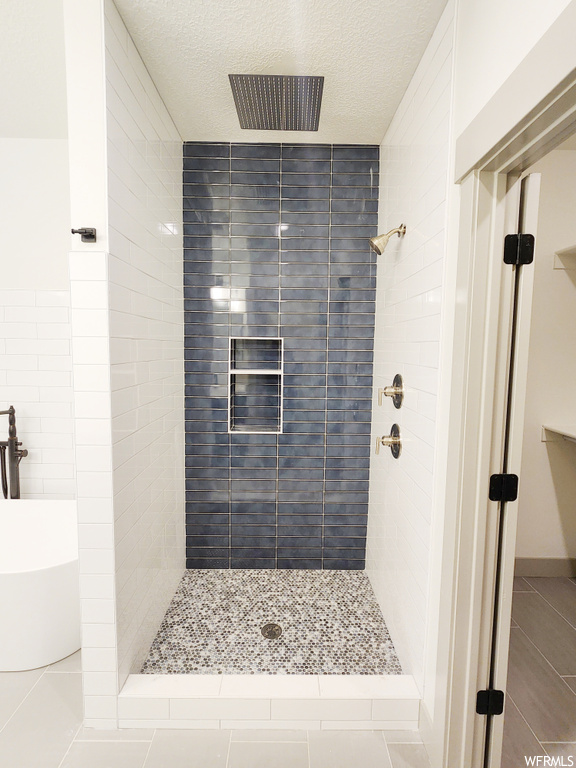 Bathroom with tile floors, tiled shower, and a textured ceiling