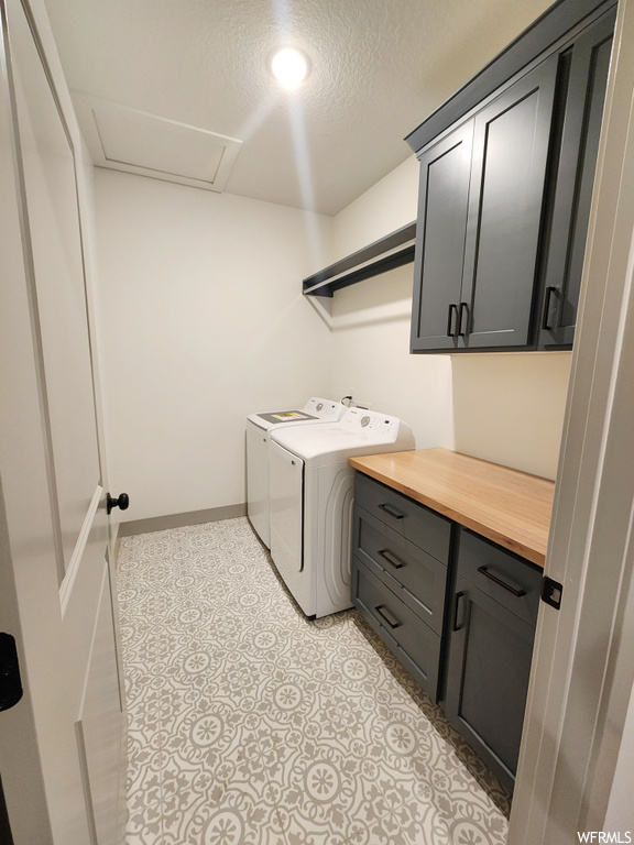 Clothes washing area featuring cabinets, washer and clothes dryer, a textured ceiling, and light tile flooring