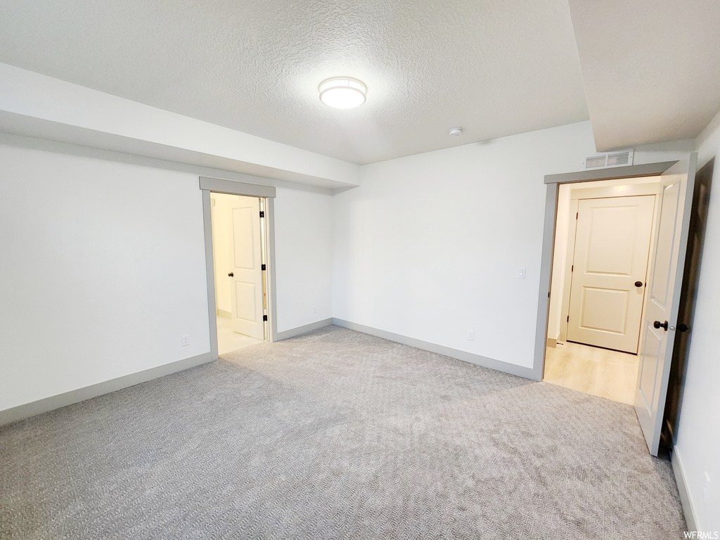 Empty room featuring light carpet and a textured ceiling