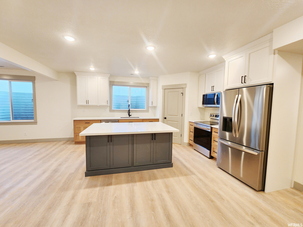 Kitchen featuring light hardwood / wood-style flooring, white cabinetry, and appliances with stainless steel finishes