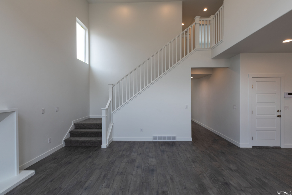 Stairway featuring dark wood-type flooring and a towering ceiling