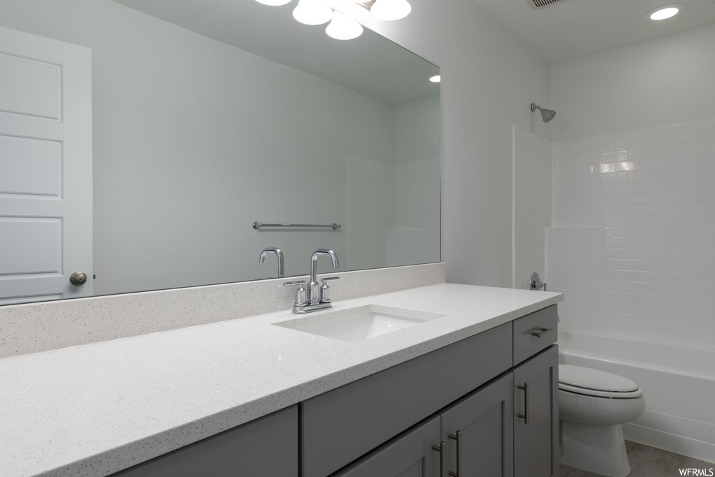 Full bathroom with tiled shower / bath combo, toilet, and vanity with extensive cabinet space
