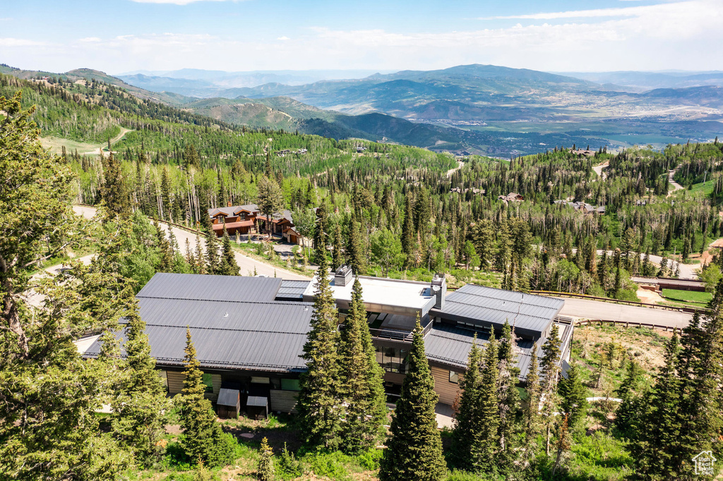 View of subject property featuring a mountainous background and a forest