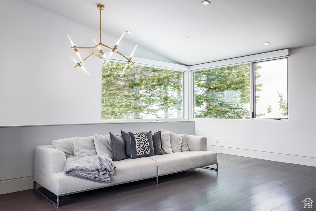 Living room with dark wood-style floors, vaulted ceiling, and a chandelier