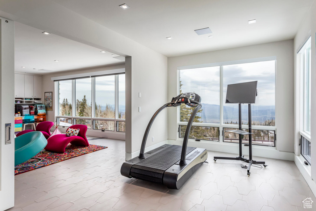 Exercise area featuring a wealth of natural light, light tile floors, and a mountain view