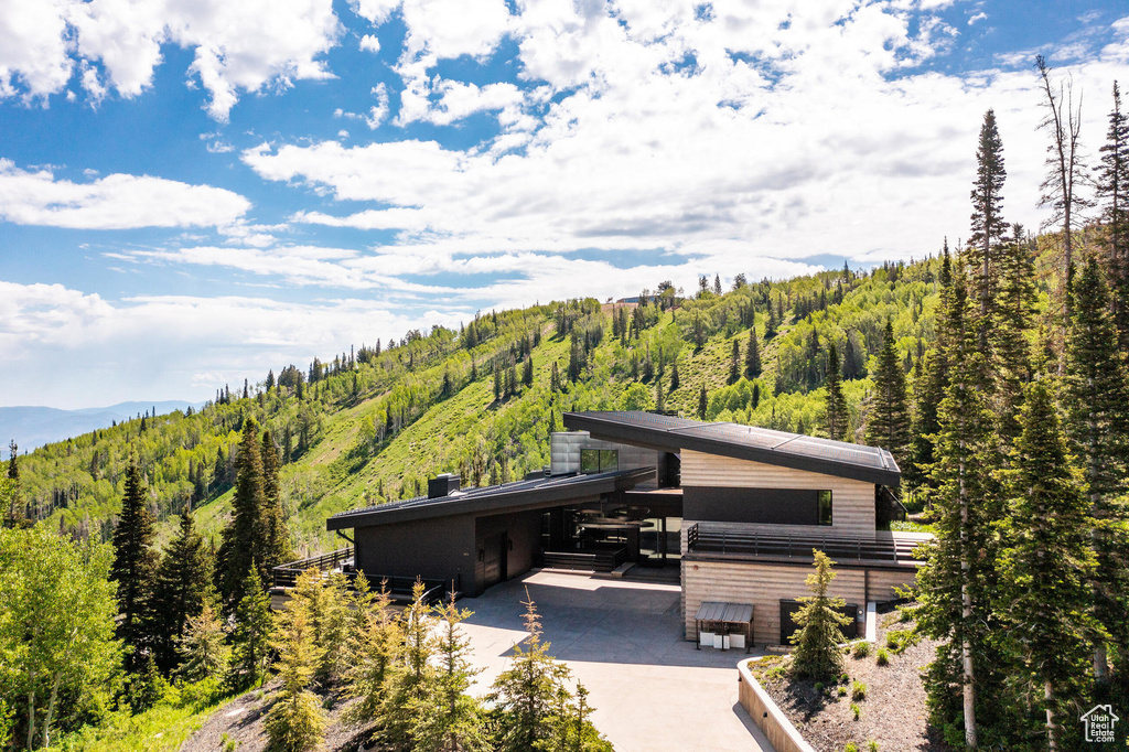 View of front of property featuring a forest view, concrete driveway, and a mountain view