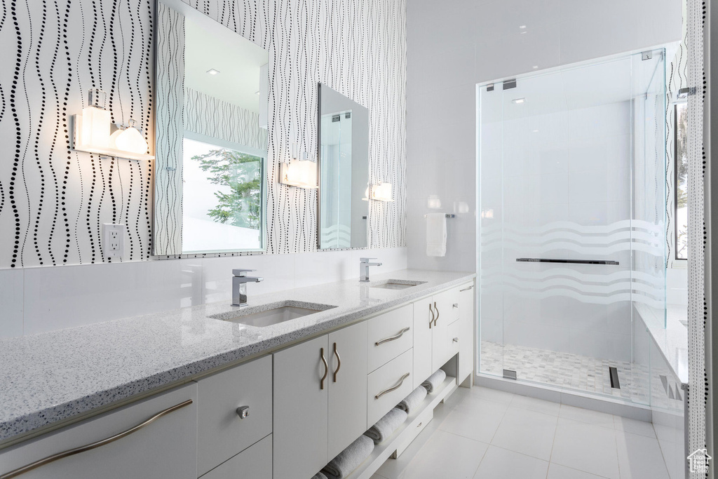 Full bath featuring a stall shower, double vanity, and tile patterned floors