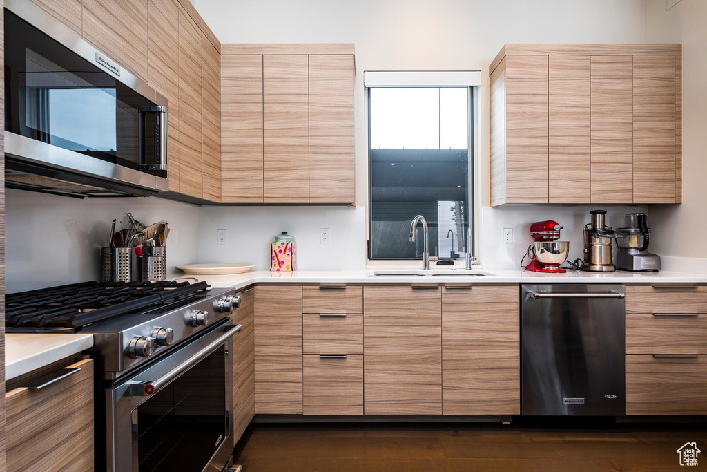Kitchen with stainless steel appliances, a sink, modern cabinets, and light countertops