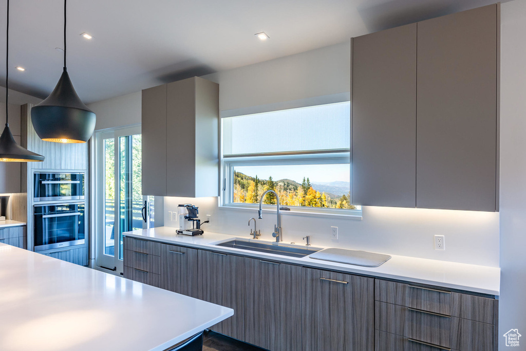 Kitchen featuring a sink, modern cabinets, stainless steel double oven, and gray cabinets