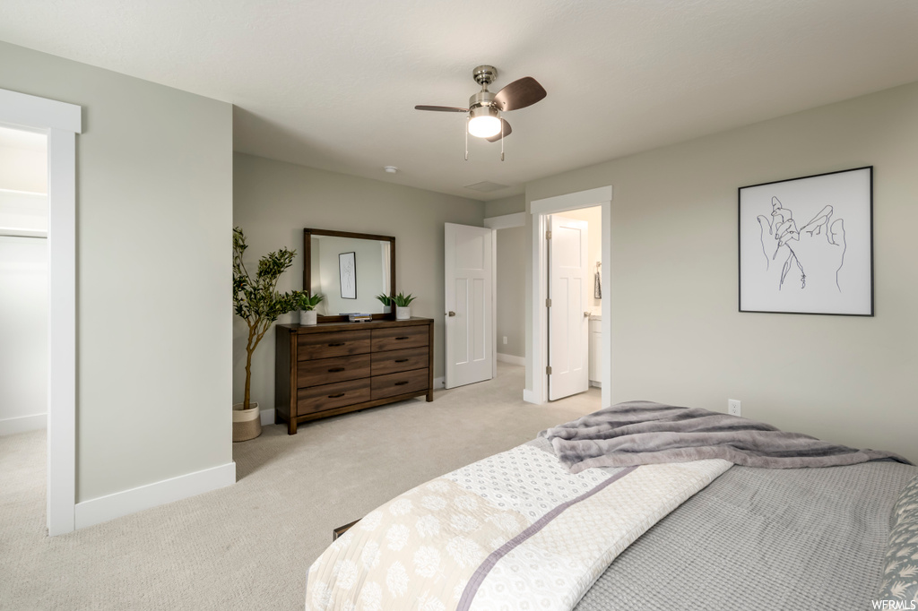 Bedroom with light colored carpet, ensuite bath, and ceiling fan
