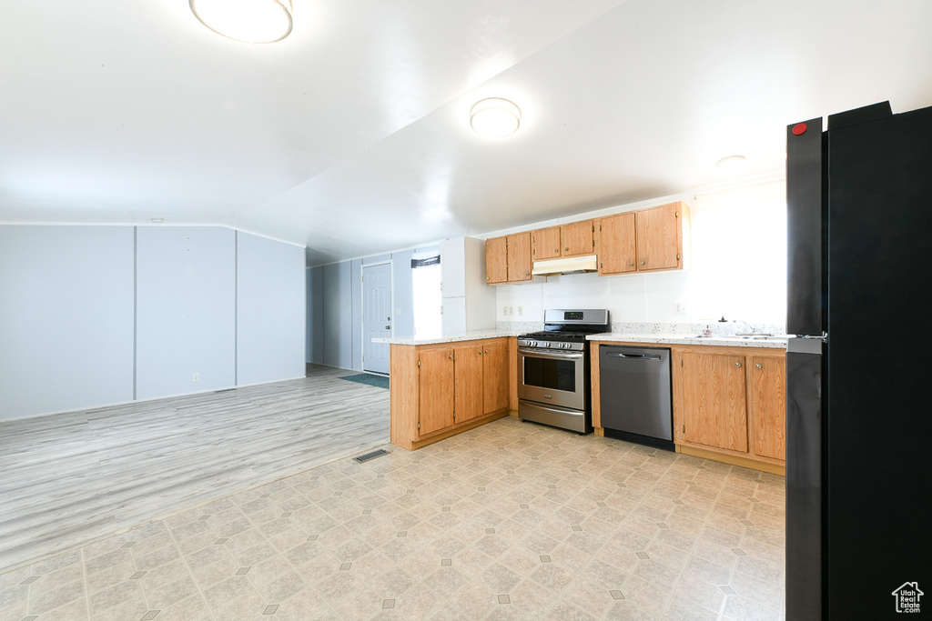 Kitchen with lofted ceiling, appliances with stainless steel finishes, light tile flooring, and kitchen peninsula