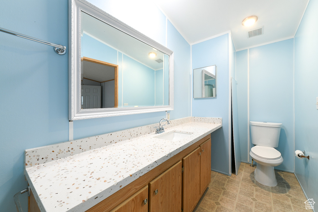 Bathroom featuring lofted ceiling, vanity, toilet, and tile flooring