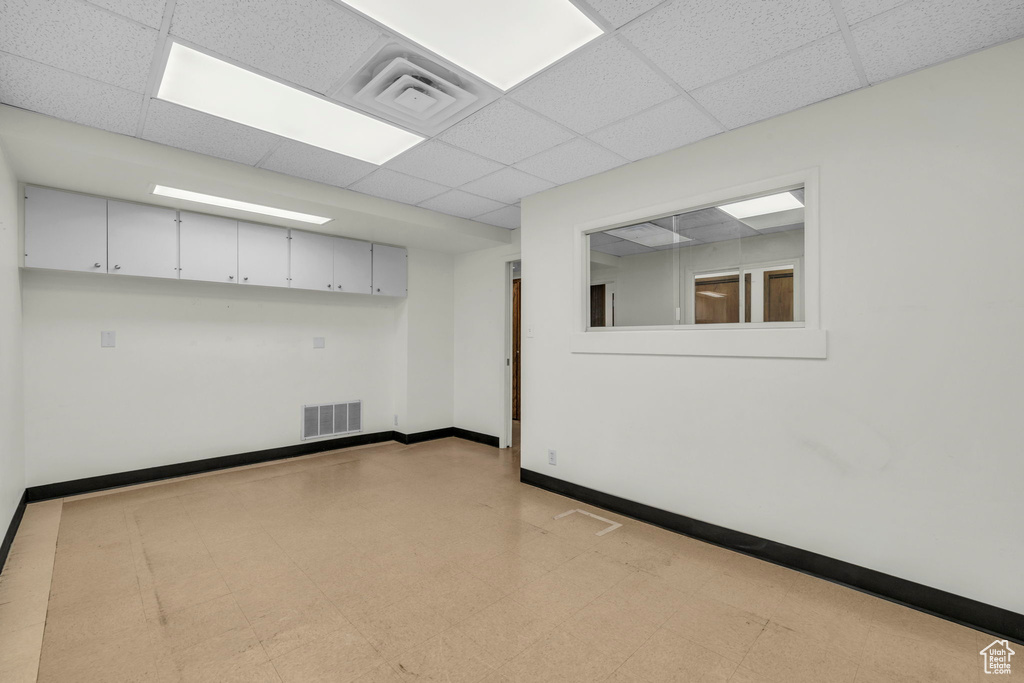 Unfurnished room with a drop ceiling and light tile flooring
