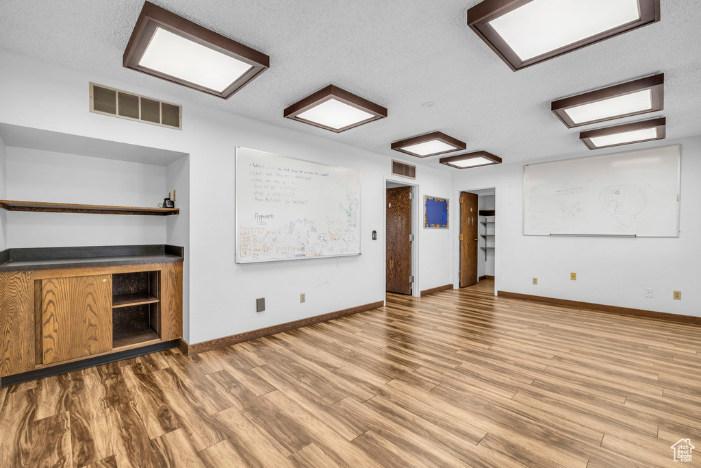 Spare room with a textured ceiling and light hardwood / wood-style floors