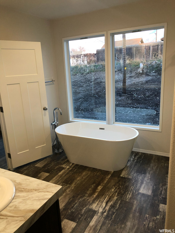 Bathroom with hardwood / wood-style floors, a wealth of natural light, vanity, and a tub