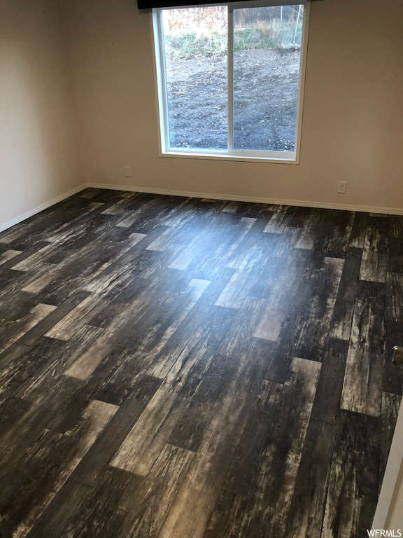 Spare room featuring dark wood-type flooring and a healthy amount of sunlight