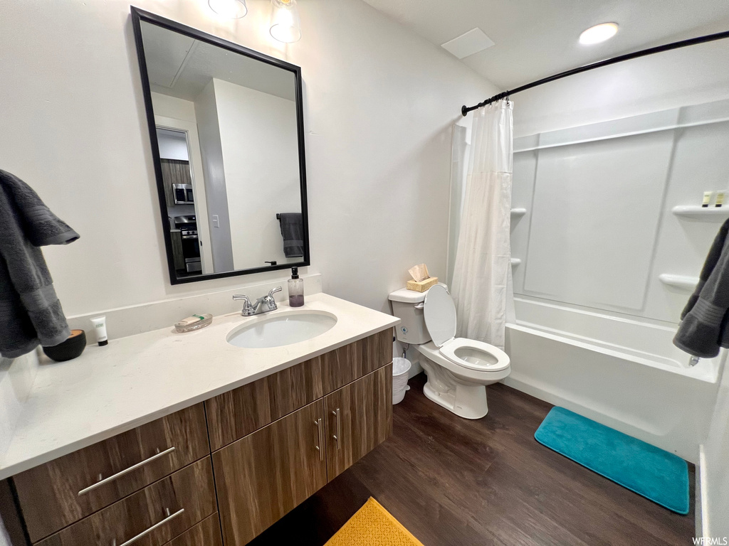 Full bathroom with wood-type flooring, shower / bath combo, toilet, and oversized vanity