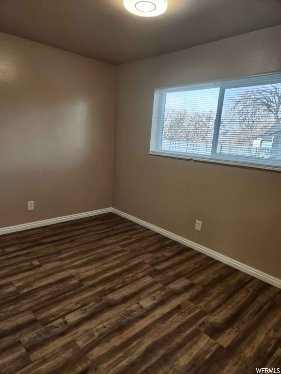 Unfurnished room with dark wood-type flooring