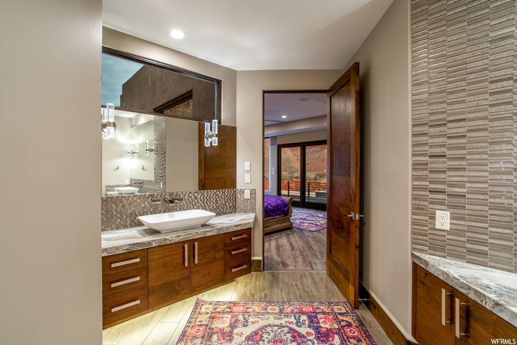 Bathroom featuring backsplash, vanity with extensive cabinet space, and hardwood / wood-style flooring