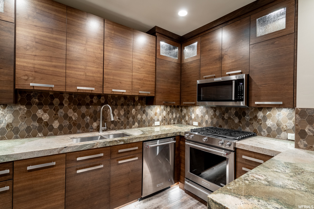 Kitchen featuring sink, tasteful backsplash, appliances with stainless steel finishes, and light stone counters