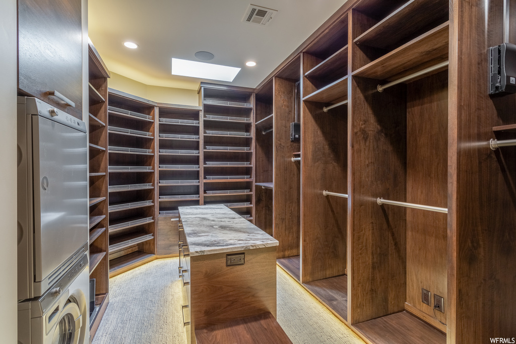 Spacious closet with a skylight, light wood-type flooring, and stacked washer and dryer