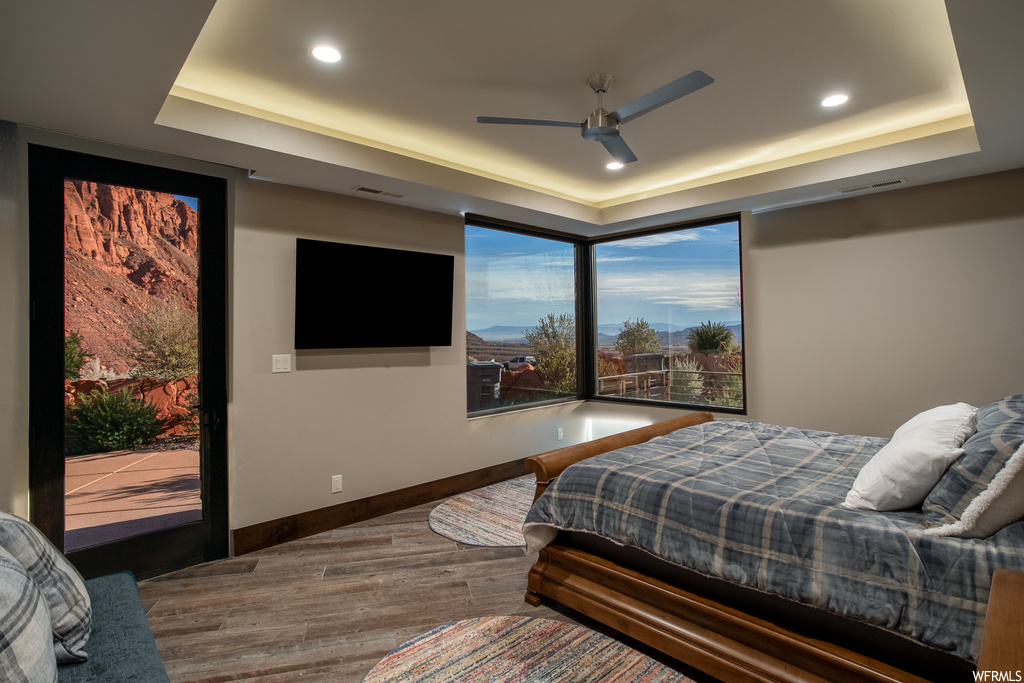 Bedroom featuring dark wood-type flooring, a raised ceiling, and ceiling fan