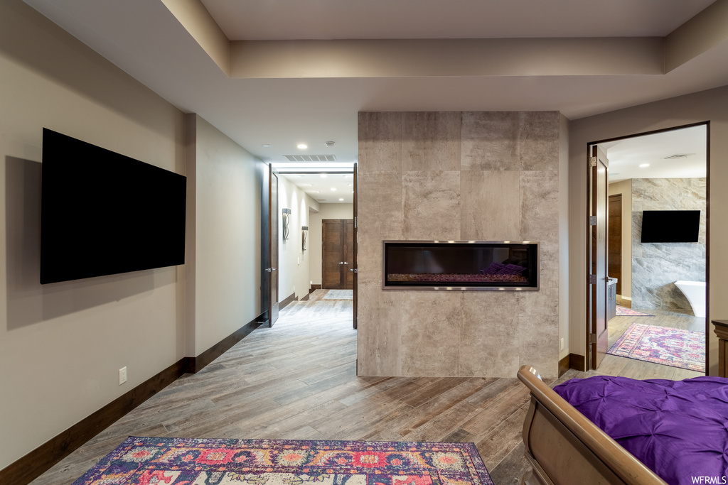 Bedroom featuring connected bathroom, a fireplace, and light hardwood / wood-style floors