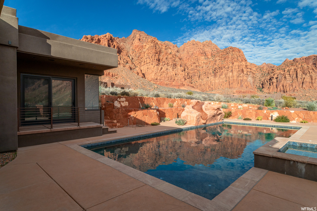 View of pool featuring a patio, an outdoor hot tub, and a mountain view