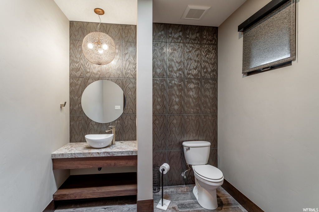 Bathroom featuring toilet, tile walls, and vanity with extensive cabinet space