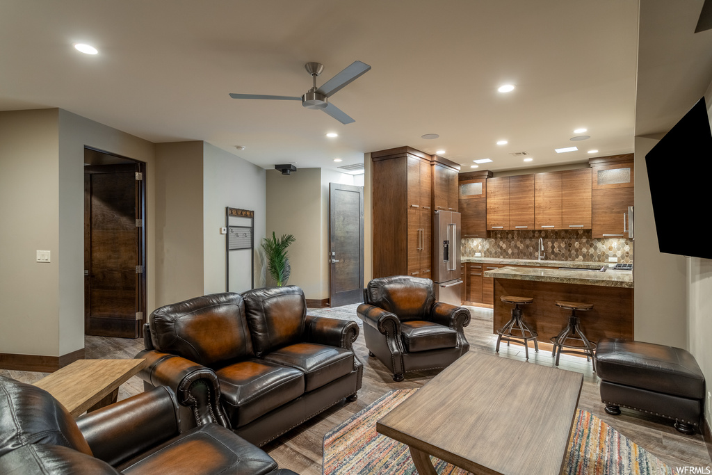 Living room featuring wood-type flooring, indoor bar, and ceiling fan