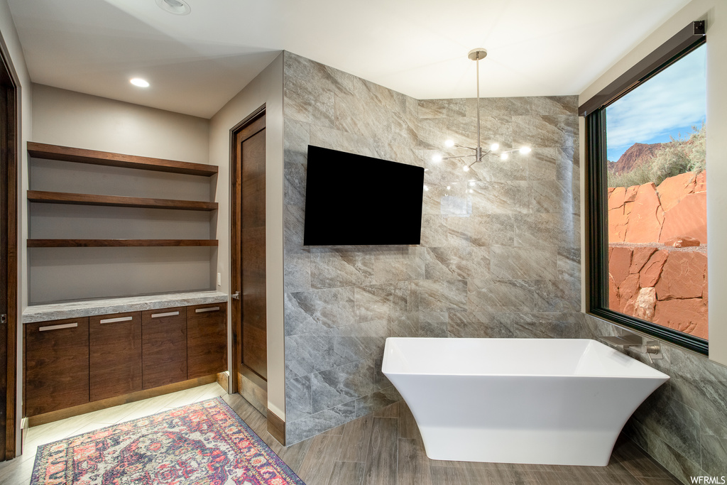 Bathroom with tile flooring, tile walls, a bath to relax in, and a tile fireplace
