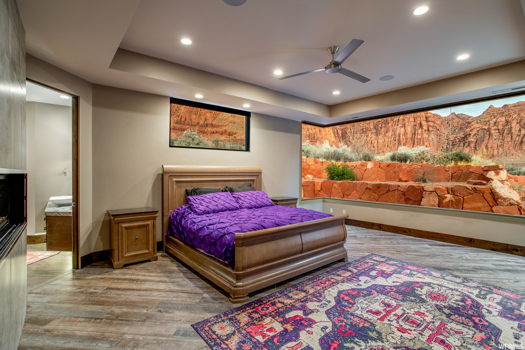 Bedroom with connected bathroom, ceiling fan, and light hardwood / wood-style flooring