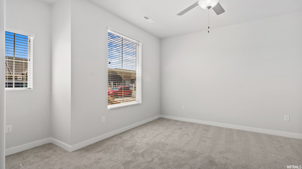 Carpeted spare room featuring ceiling fan