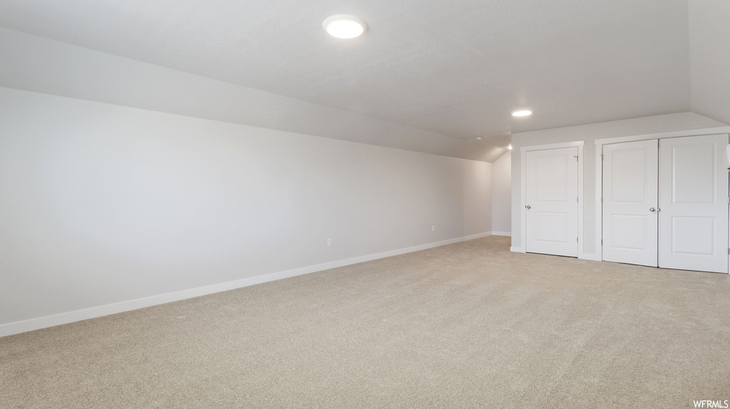 Interior space featuring light colored carpet and lofted ceiling