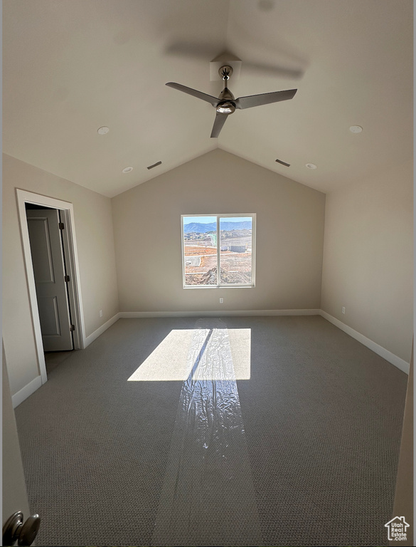 Carpeted spare room with vaulted ceiling and ceiling fan