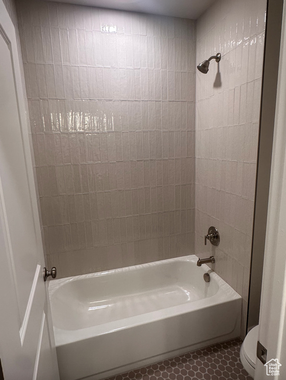 Bathroom featuring tiled shower / bath combo, toilet, and tile patterned floors