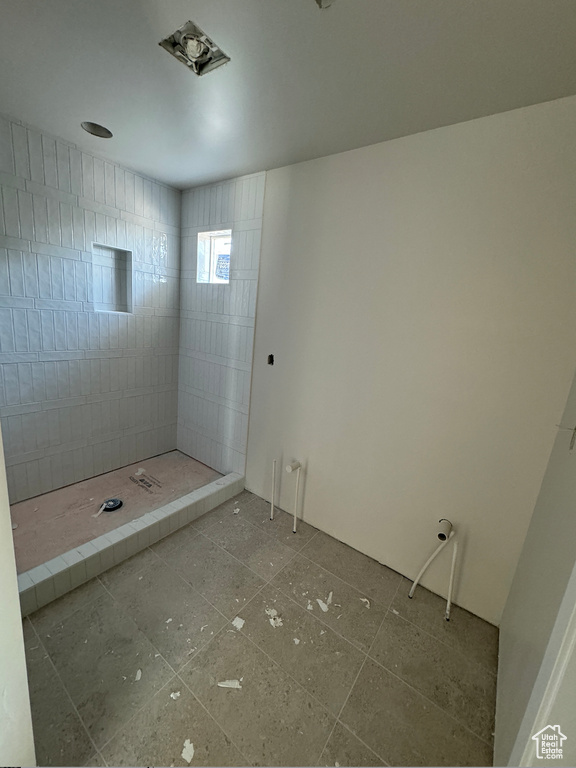 Bathroom with tile patterned floors and a tile shower