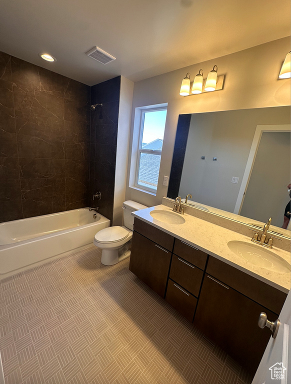 Full bathroom with vanity, tiled shower / bath combo, and toilet