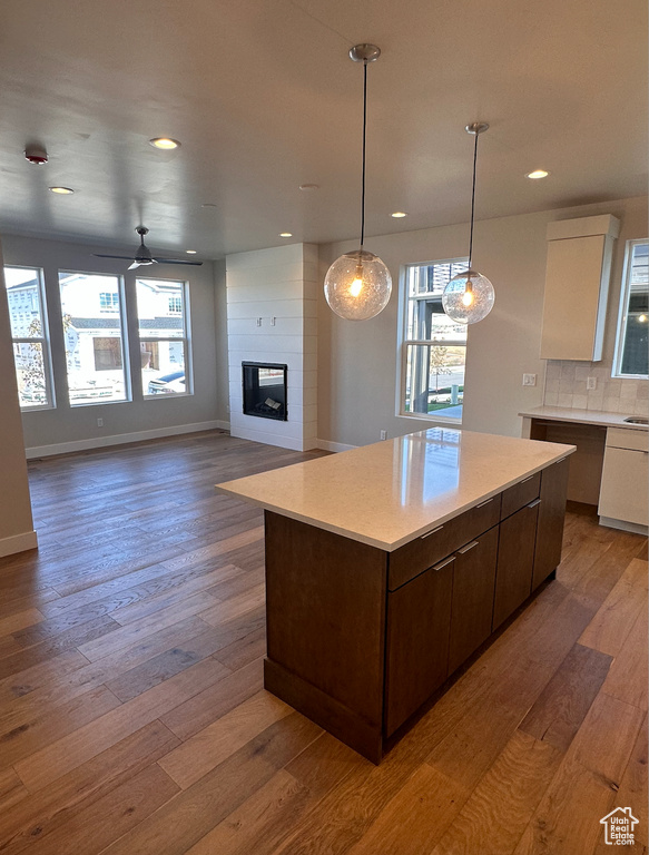 Kitchen featuring a large fireplace, white cabinets, ceiling fan, and hardwood / wood-style floors