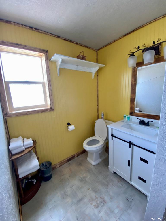 Bathroom with a textured ceiling, toilet, vanity with extensive cabinet space, and tile flooring