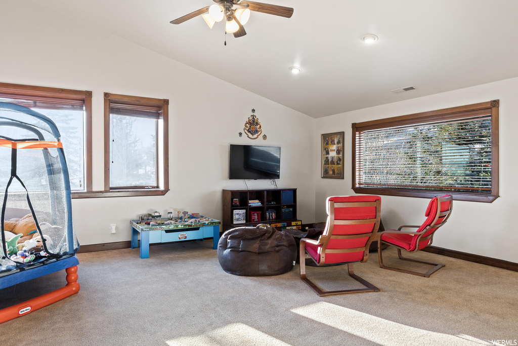 Living area with vaulted ceiling, carpet flooring, and ceiling fan