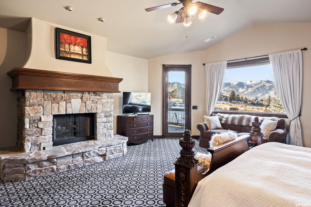 Bedroom with a stone fireplace, carpet floors, access to outside, and ceiling fan