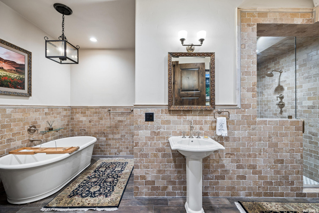 Bathroom with sink, shower with separate bathtub, backsplash, and a notable chandelier