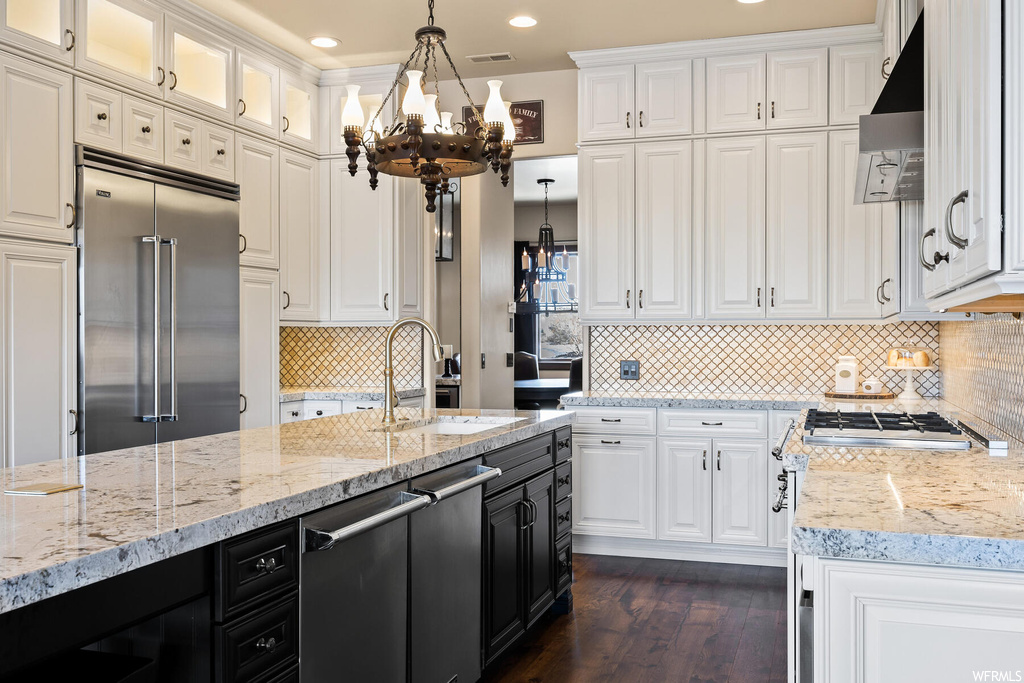 Kitchen featuring hanging light fixtures, a chandelier, appliances with stainless steel finishes, and white cabinets